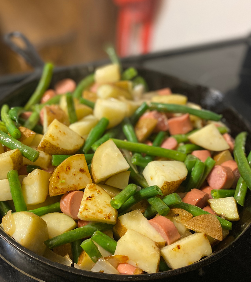 Poor Man's Meal: hot dogs, potatoes, and green beans cooking in a cast iron skillett
