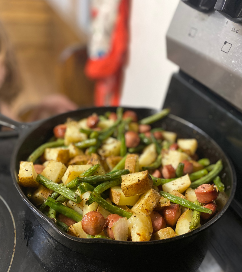 Poor Man's Meal - Potatoes, hot dogs, green beans in a cast iron skillet