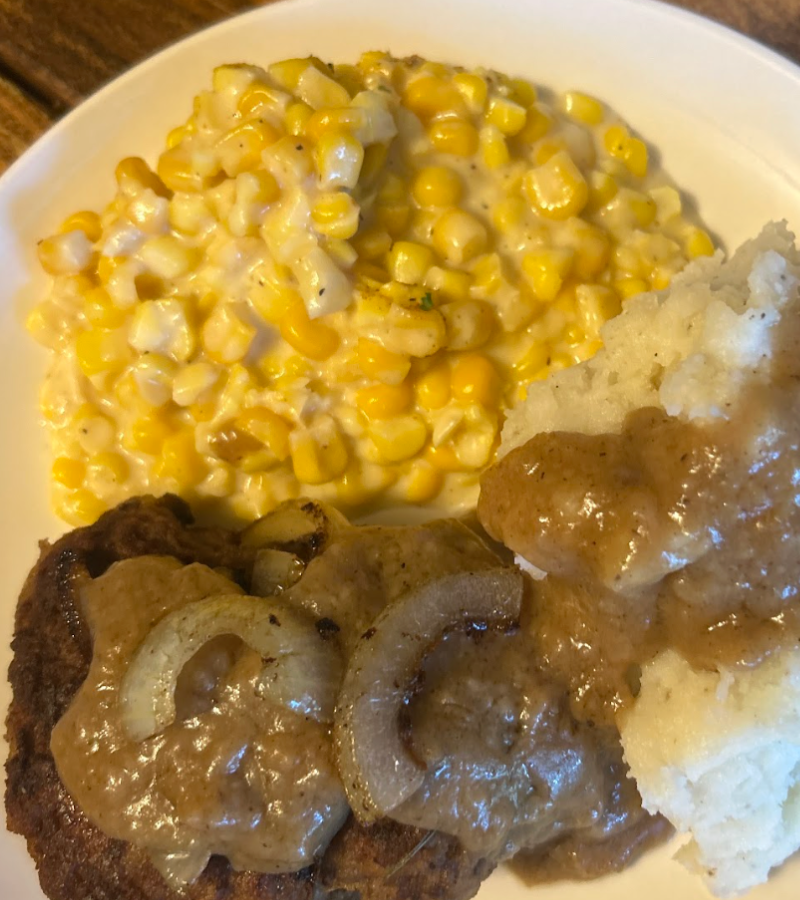 plate of salisbury steak with gravy & onions, mashed potatoes, and creamed corn